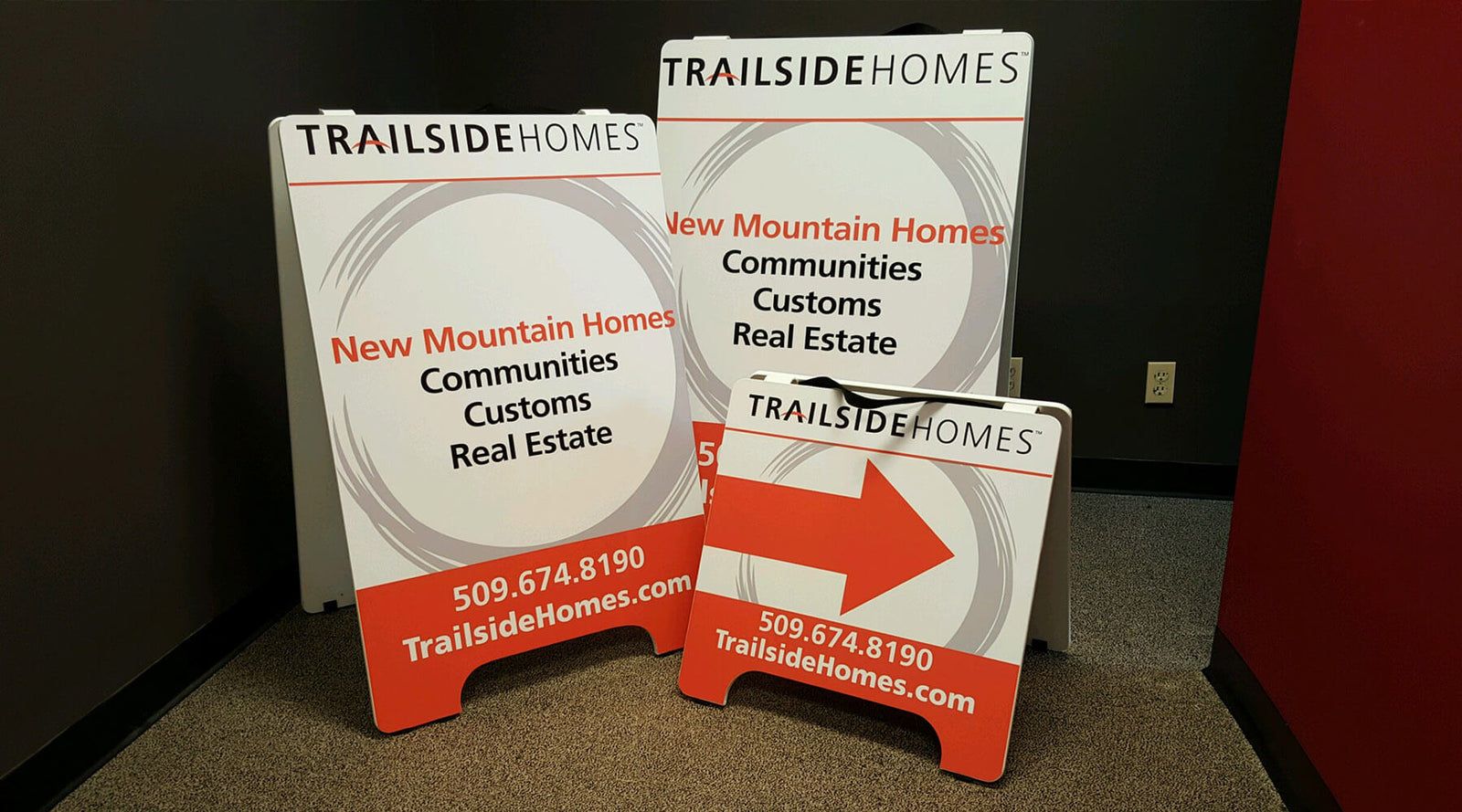 Three different sized white and orange A-frame signs for Trailside Homes by Ardor Printing in an office setting.