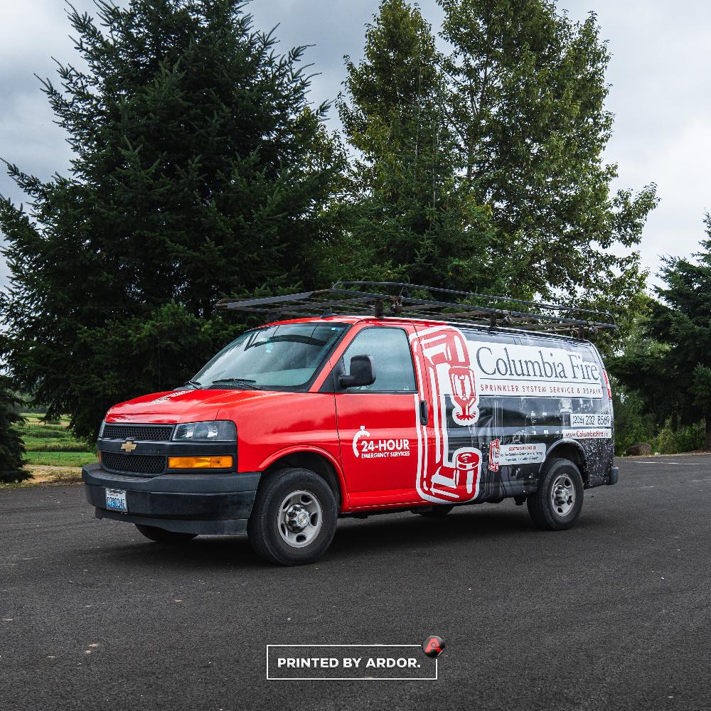 Red and black Columbia Fire van wrap featuring company branding, 24-hour service, and fire sprinkler system repair information.