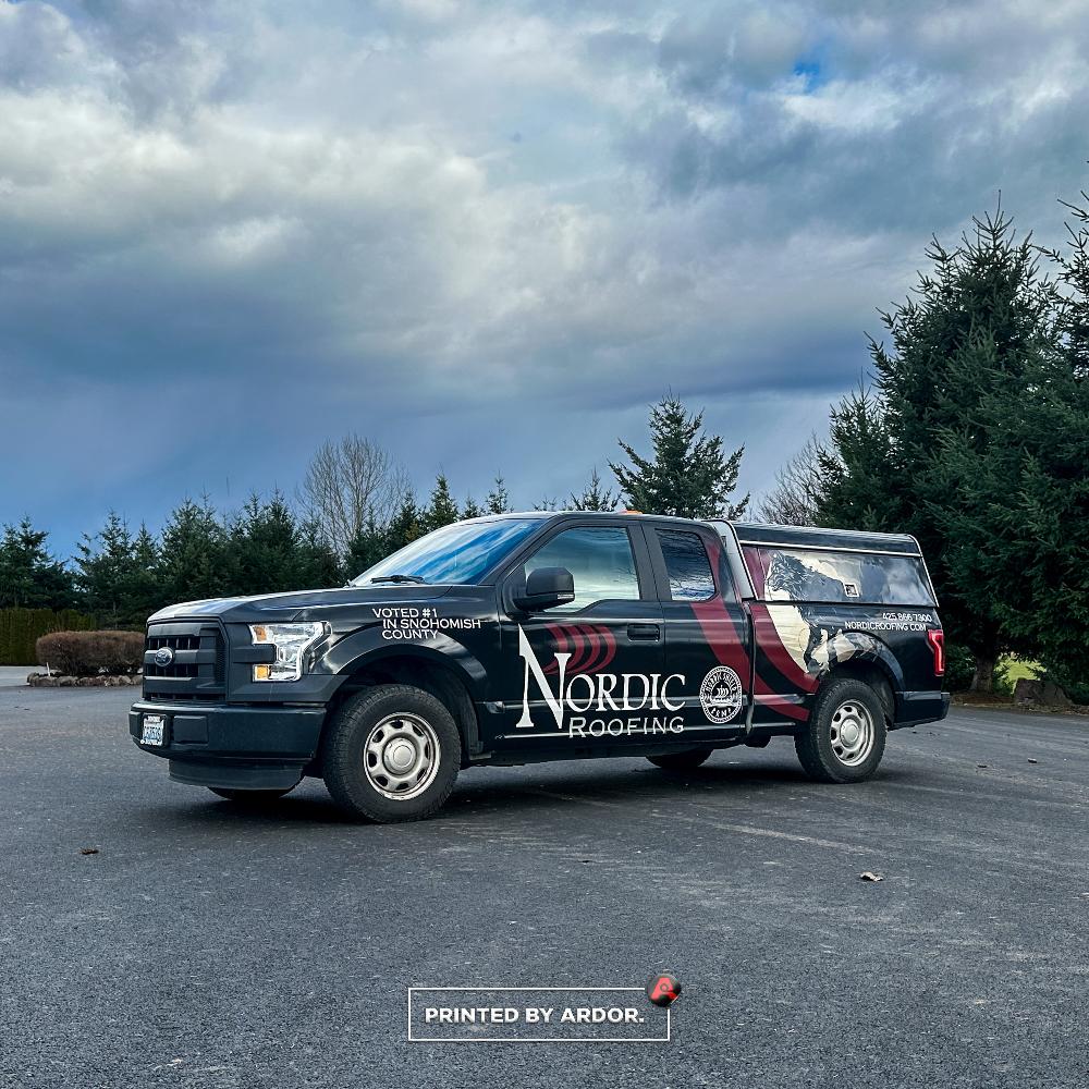 Nordic Roofing truck with a black custom wrap featuring company branding and 'Voted #1 in Snohomish County,' parked on a paved road.