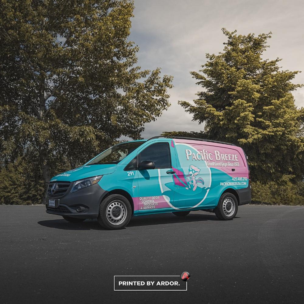Pacific Breeze van showcasing a colorful wrap with teal and pink design, advertising odor control services and products, parked near trees.
