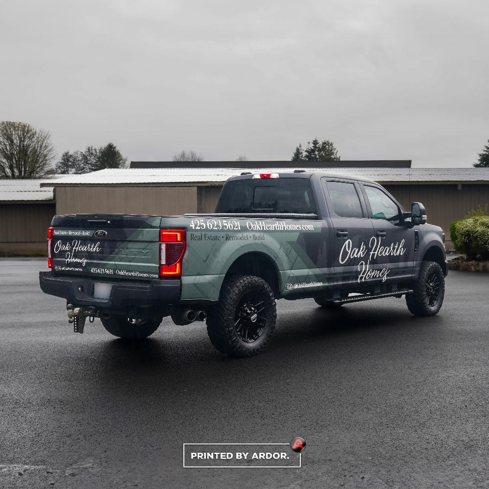 Rear view of Oak Hearth Homes’ custom wrapped Ford truck, displaying their real estate, remodel, and build services with contact details.