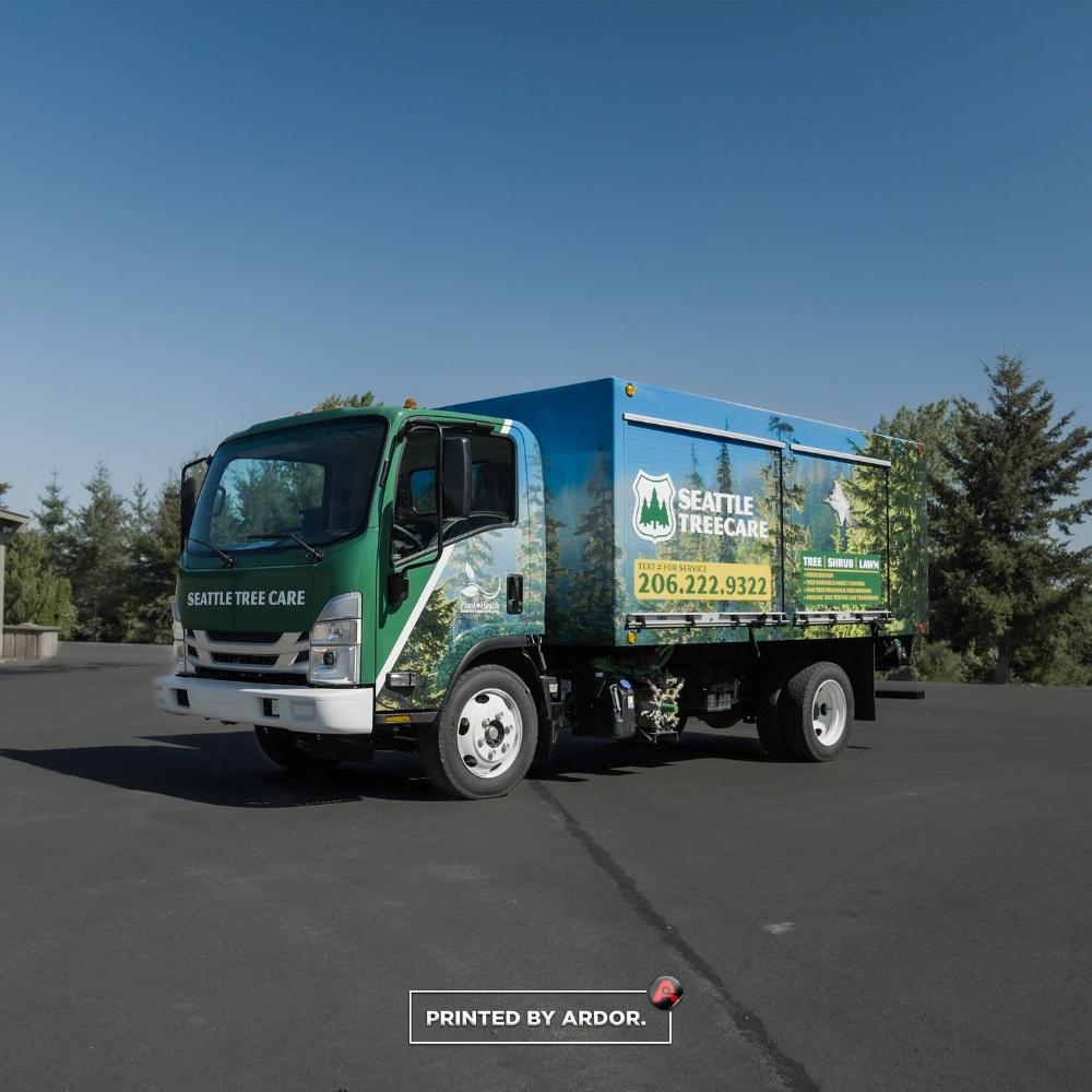 Seattle Tree Care truck with a green and blue custom wrap, featuring tree and lawn care services, company contact info, and nature-themed graphics.