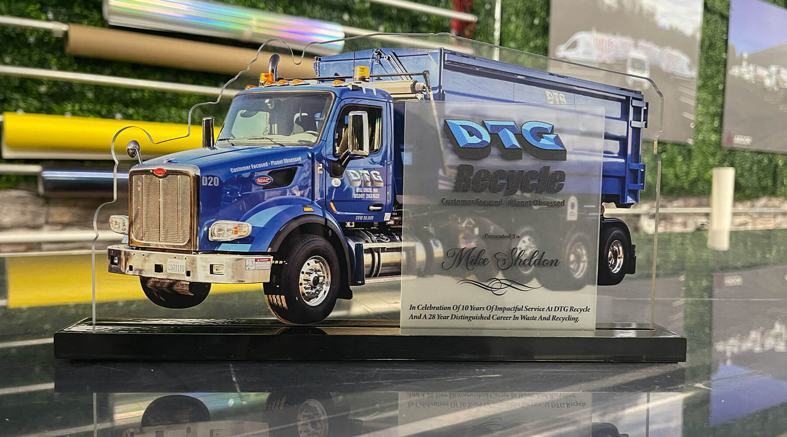Award plaque featuring a blue DTG Recycle Peterbilt dump truck printed on glass using flatbed printing technology