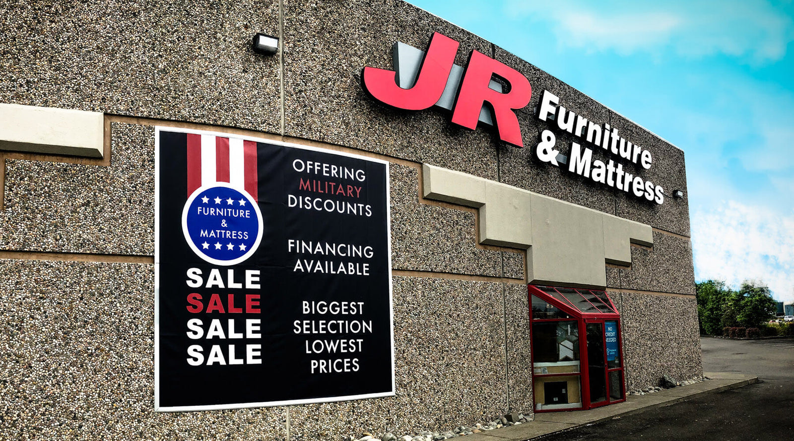 Large banner display and illuminated channel lettering sign for JR Furniture and Mattress on a sunny summer day
