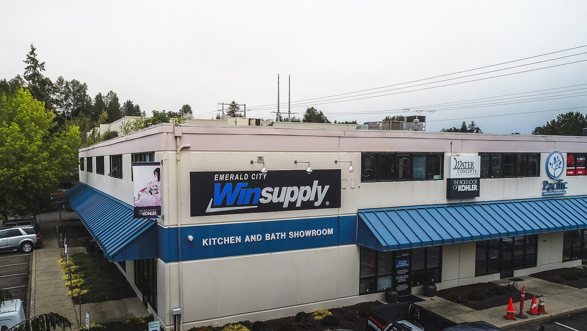 Two-story Emerald City Winsupply kitchen and bath showroom with a large Winsupply building sign above blue awnings