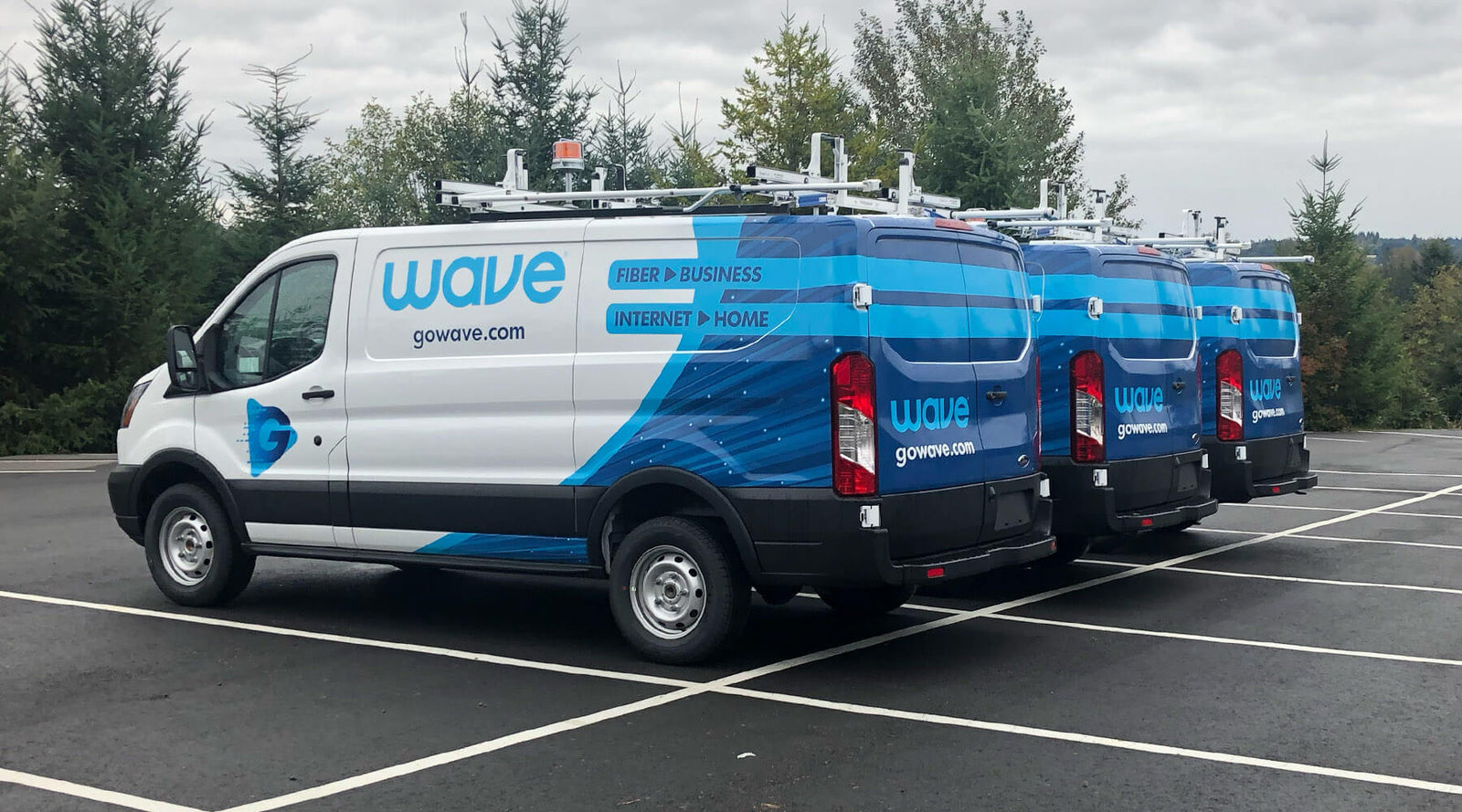 Three professionally wrapped vans showcasing different designs, illustrating the range of possibilities when considering how much does it cost to get a car wrapped.