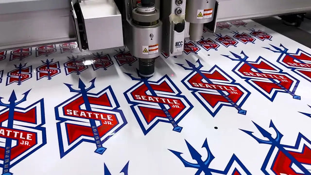 Zünd digital cutter cutting printed red, white and blue Seattle Jr. hockey logo stickers on white vinyl