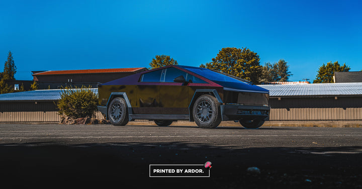 Tesla Cybertruck with a red and black iridescent color-shift wrap parked on asphalt