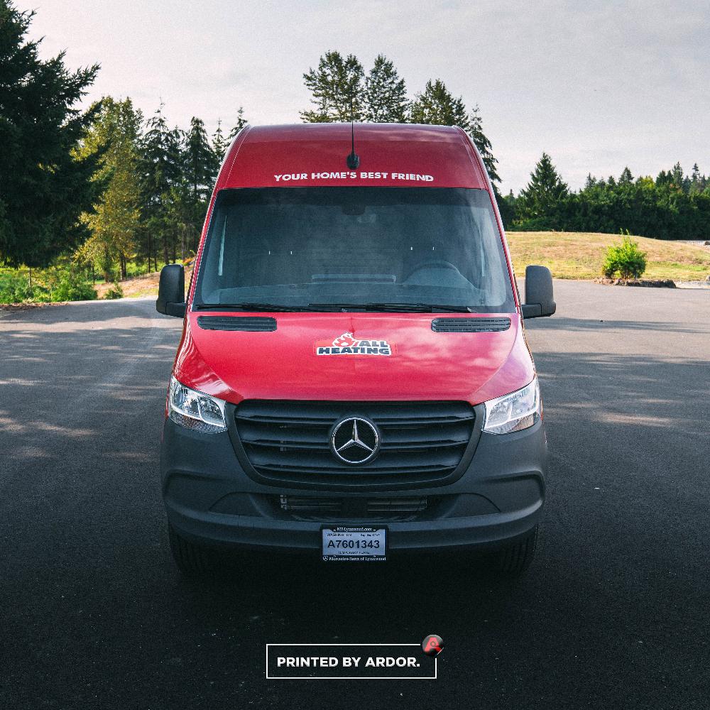 Red All Heating van wrap with company logo and slogan on the windshield, providing heating and cooling services, parked on a road.