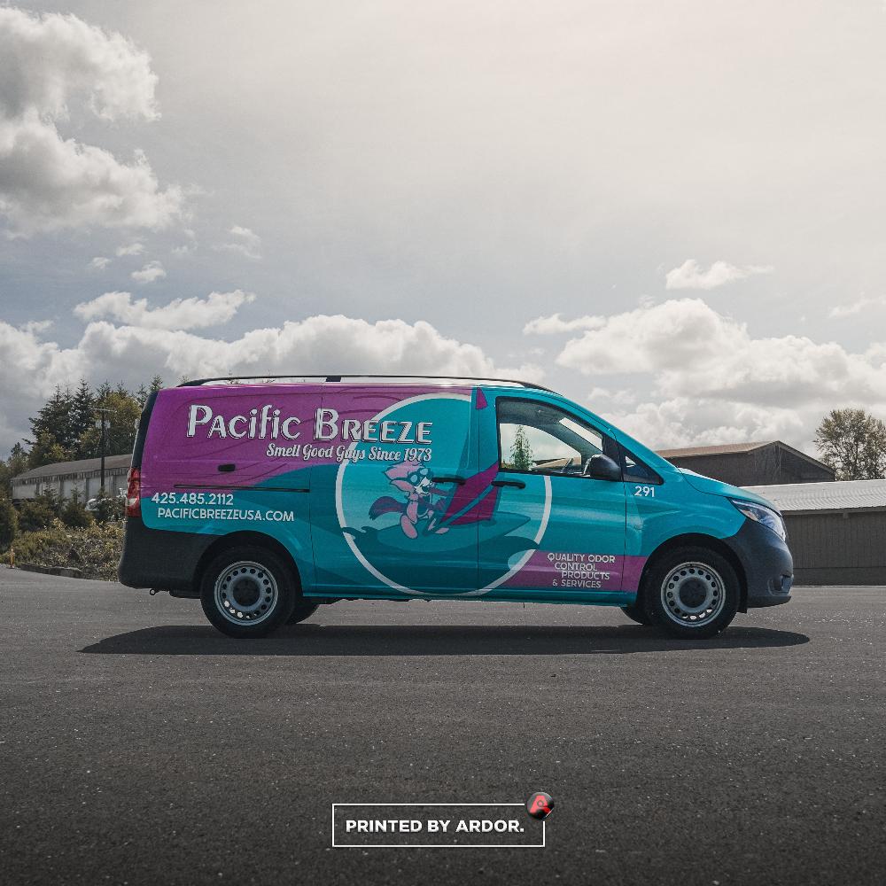 Side profile of Pacific Breeze van wrap showcasing a colorful pink and teal wrap with the company logo and contact details.