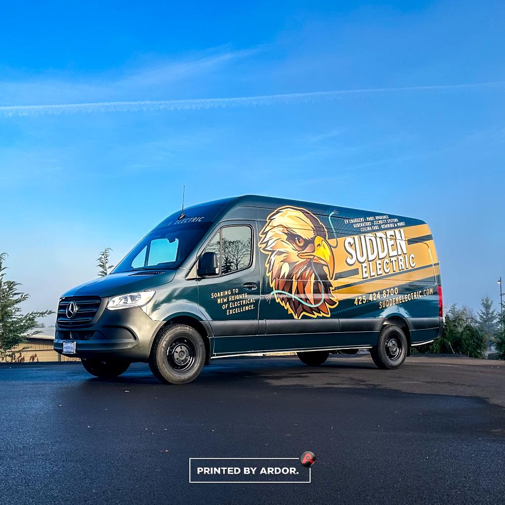 Mercedes van wrapped with Sudden Electric branding, featuring a powerful eagle design and company contact information, including website and phone.