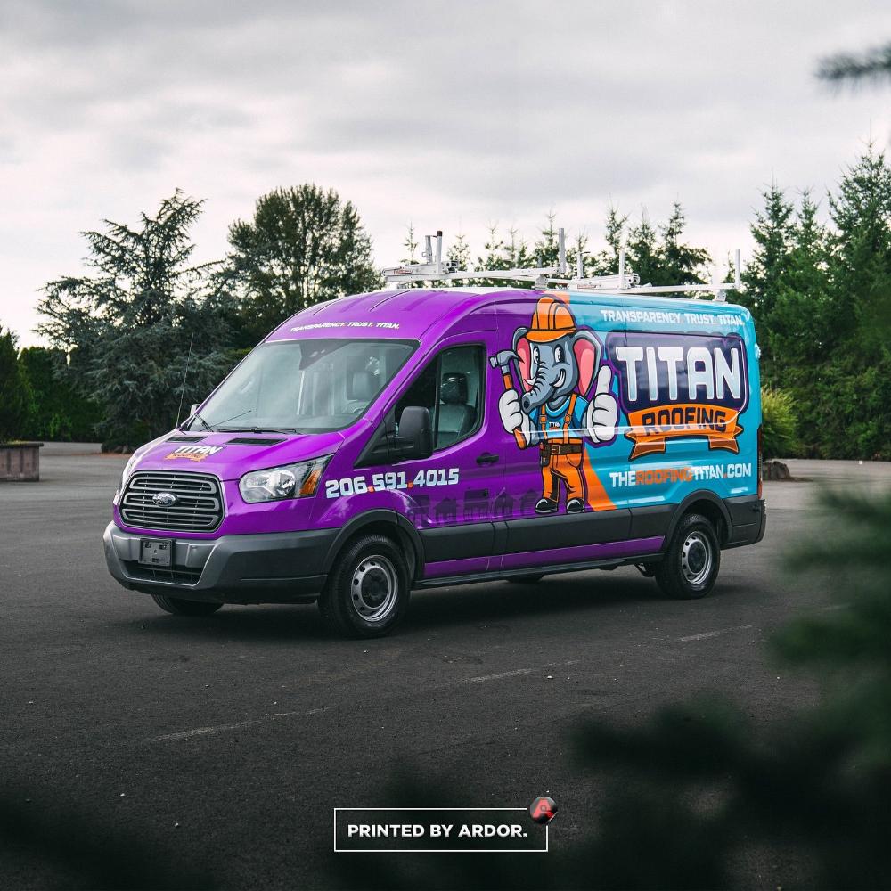 Titan Roofing van with a bold purple and blue wrap featuring a cartoon elephant mascot, company branding, and contact info, parked on a paved road.