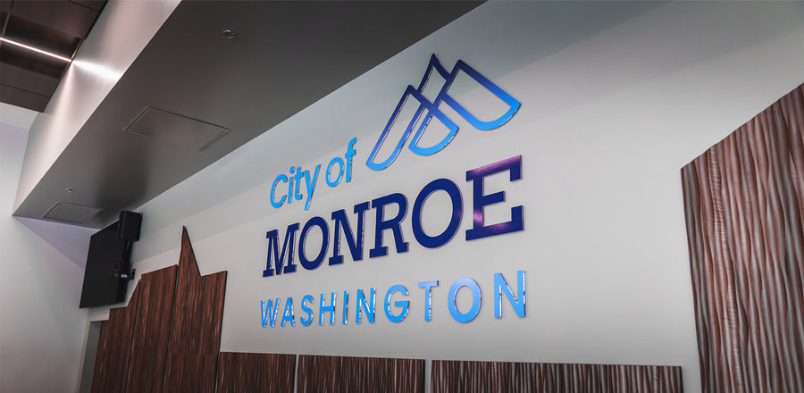 Acrylic lobby logo sign for the City of Monroe, Washington, mounted on a white wall