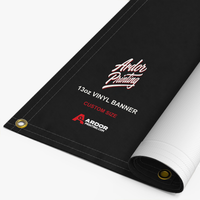 Custom 13oz vinyl banner printed with Ardor Printing branding, partly rolled to show the hemmed edge and brass grommets