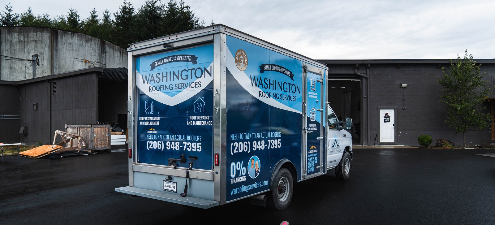 Box truck wrapped in blue Washington Roofing Services graphics on the side and rear, with phone number and services