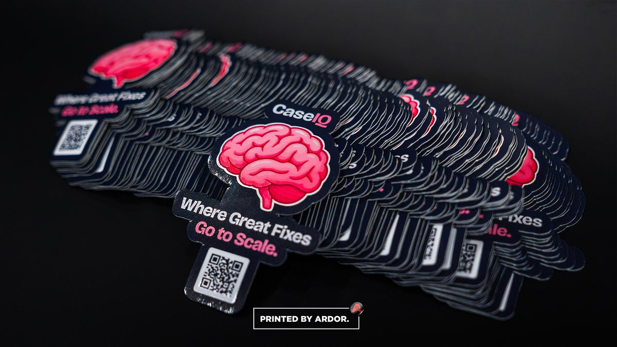Stacks of CaseIQ die-cut QR code stickers with a pink brain logo, printed and cut by Ardor Printing
