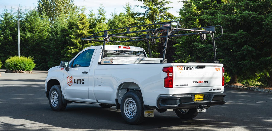 White Chevy Silverado work truck with UMC door logos and tailgate lettering