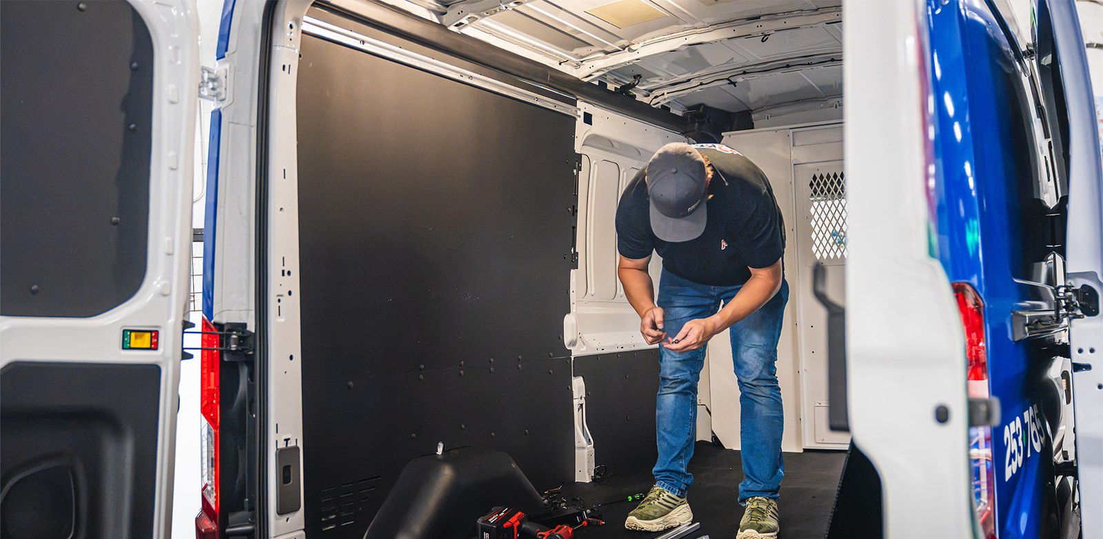Ardor Printing installer working inside a cargo van during an interior upfit, with tools and parts on the floor