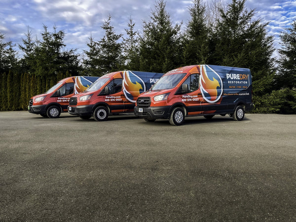 Three PureDry Restoration vans with blue and orange fleet wraps, printed and installed by Ardor Printing