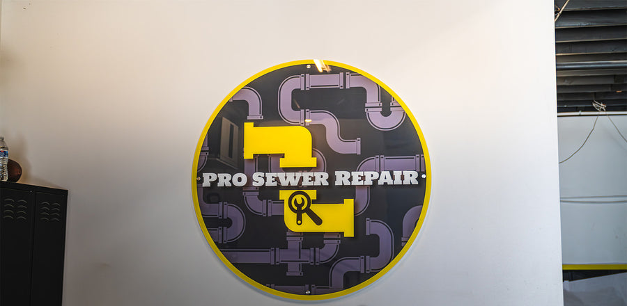 Round acrylic logo sign for Pro Sewer Repair mounted on an office wall