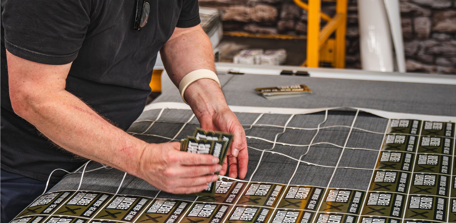 Ardor Printing team member pulling freshly cut custom stickers off a digital cutting table in the shop