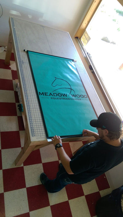Ardor Printing team finishing a vinyl banner with hems and grommets by Ardor Printing