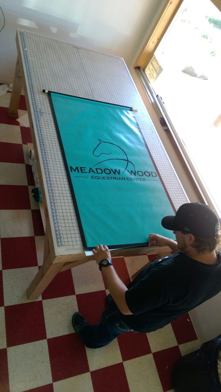 Ardor Printing team member finishing a vinyl banner with hems and grommets in the Snohomish shop